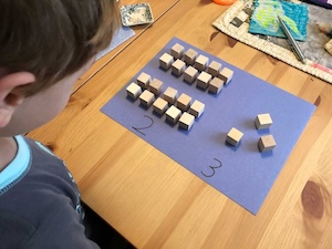 Wooden blocks arranged to show two groups of ten plus three singles for 23.