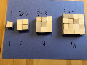 Wooden blocks arranged to show two times two, three times three, and four times four.