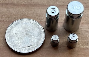 Photo showing a quarter next to weights of 1, 2, 5, and 100 grams.