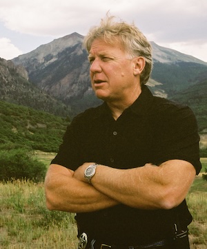 Bill Masters in a black shirt standing in front of the mountains around Telluride.