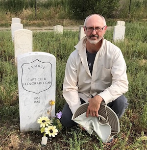 Ari Armstrong beside the tombstone of Silas Soule.